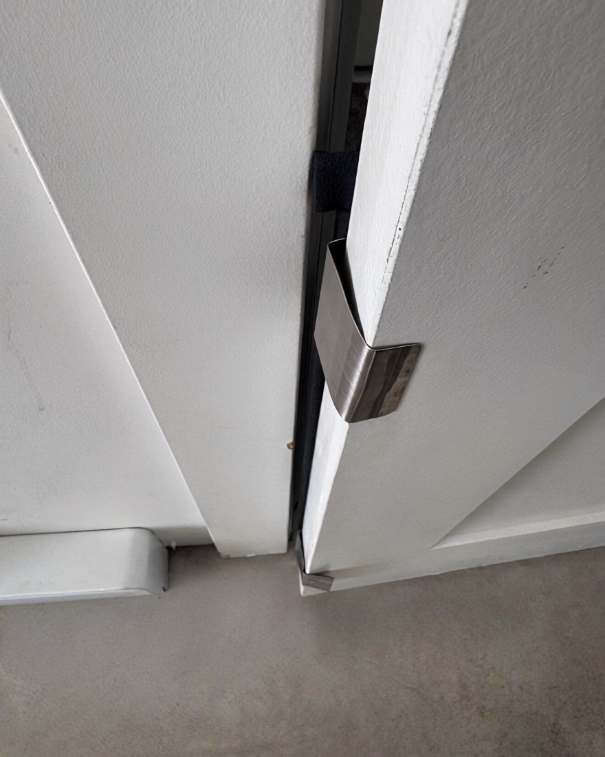 Close-up of Clawstopper J-channel clamp attached to door edge — no-damage door protector installation detail